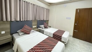A hotel room with two beds, a ceiling fan, and a wooden door. - The Asteria Hotel Bogura (Bogra)