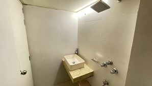 A small bathroom with a single sink, a showerhead, and a toilet. - The Asteria Hotel Bogura (Bogra)