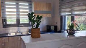A modern kitchen with wooden cabinets, a stainless steel sink, and a window with blinds.