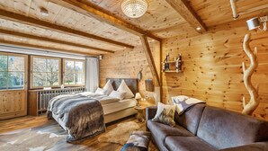 A log cabin interior with a bed, sofa, and large windows.