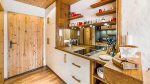 A kitchen with wooden cabinets, a built-in stove, and various kitchen utensils.