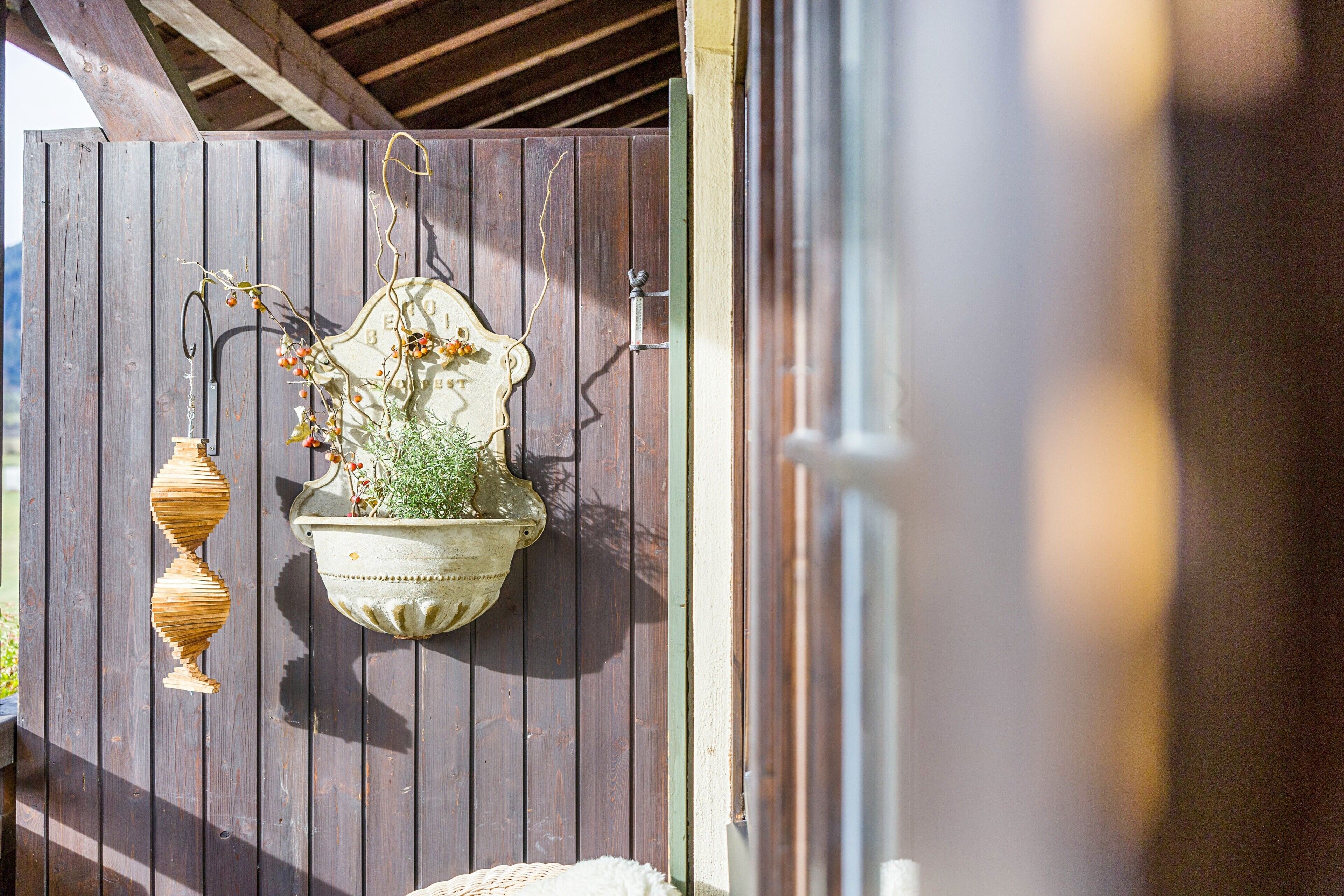 Une porte en bois ornée d’un pot suspendu et d’un élément décoratif en métal.