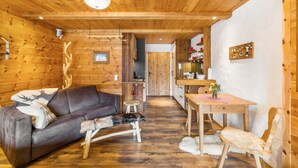 A wooden interior with a sofa, a bench, a dining table, and a chair.