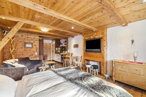 Ein gemütliches Blockhaus-Interieur mit einem Bett, einer Couch, einer Essecke und einem Kamin.