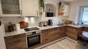 Eine moderne Küche mit Holzschränken, einem Einbauofen, einer Mikrowelle und einer Kaffeemaschine.