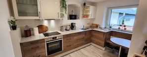 Eine moderne Küche mit Holzschränken, einem Einbauofen, einer Mikrowelle und einer Kaffeemaschine.
