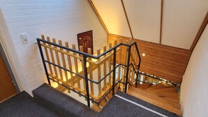 Eine Treppe mit Holzboden und Metallgeländern, weißen Backsteinwänden und einer Tür mit einem Schild.