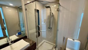 A modern bathroom with a glass-enclosed shower, a marble vanity, and a large mirror. - The Peak Towers by PSR (Pattaya)