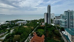 A coastal cityscape with modern high-rise buildings, a marina, and lush greenery. - The Peak Towers by PSR (Pattaya)