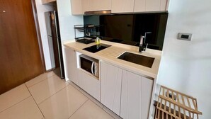 A modern kitchen with a double sink, a built-in oven, and a coffee machine. - The Peak Towers by PSR (Pattaya)