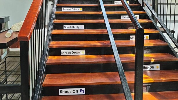 A staircase with wooden steps and metal railings, featuring motivational signs like 'Less Worry' and 'Respect Others.' - Monkey House Hostel Koh Samui (Koh Samui)