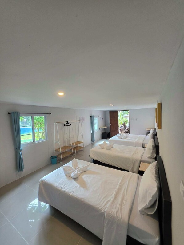 A hotel room with two beds, a window with a view, a hanging chair, and a small table.