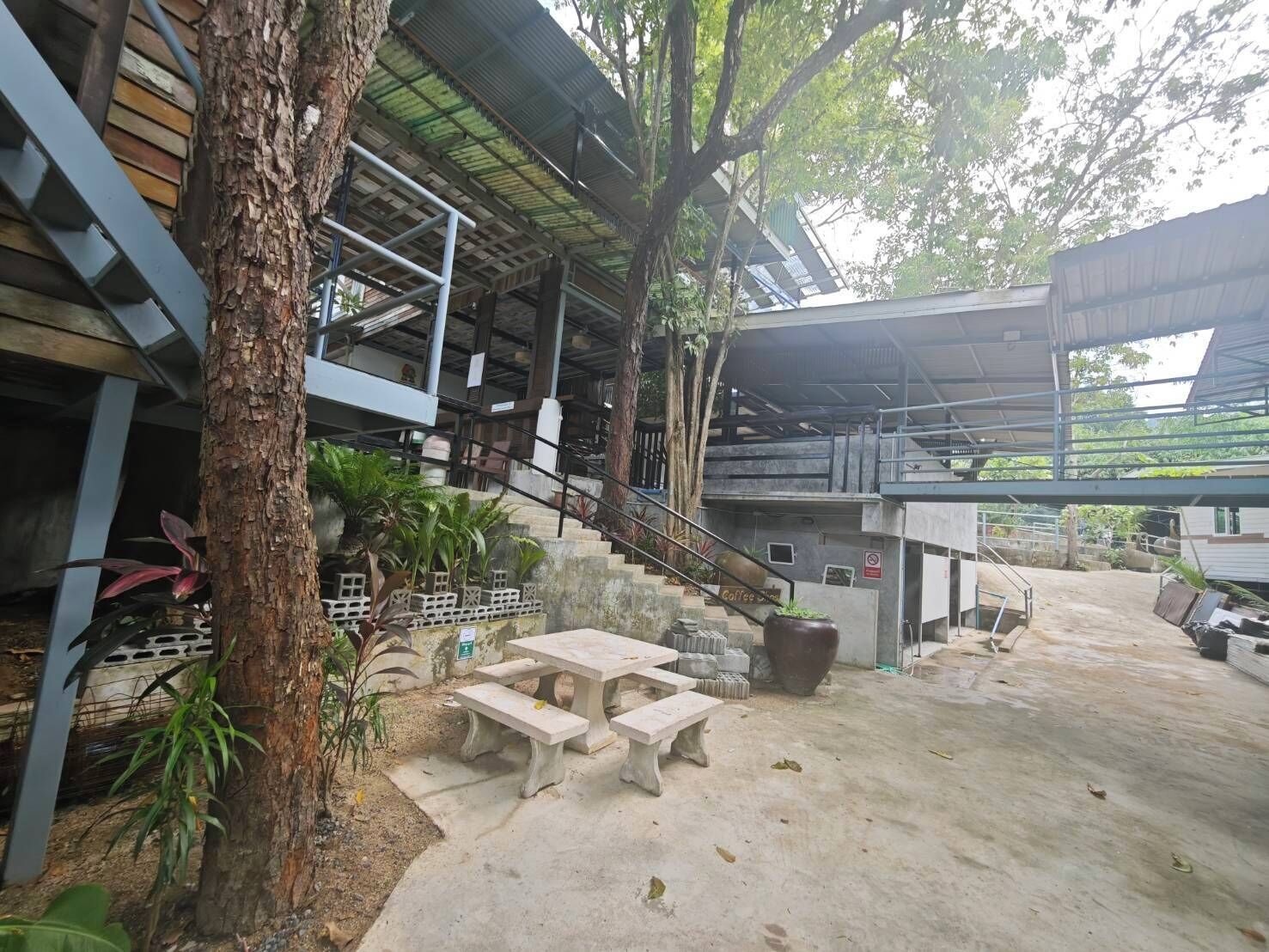 A covered outdoor area with a concrete floor, a staircase, and a picnic table.
