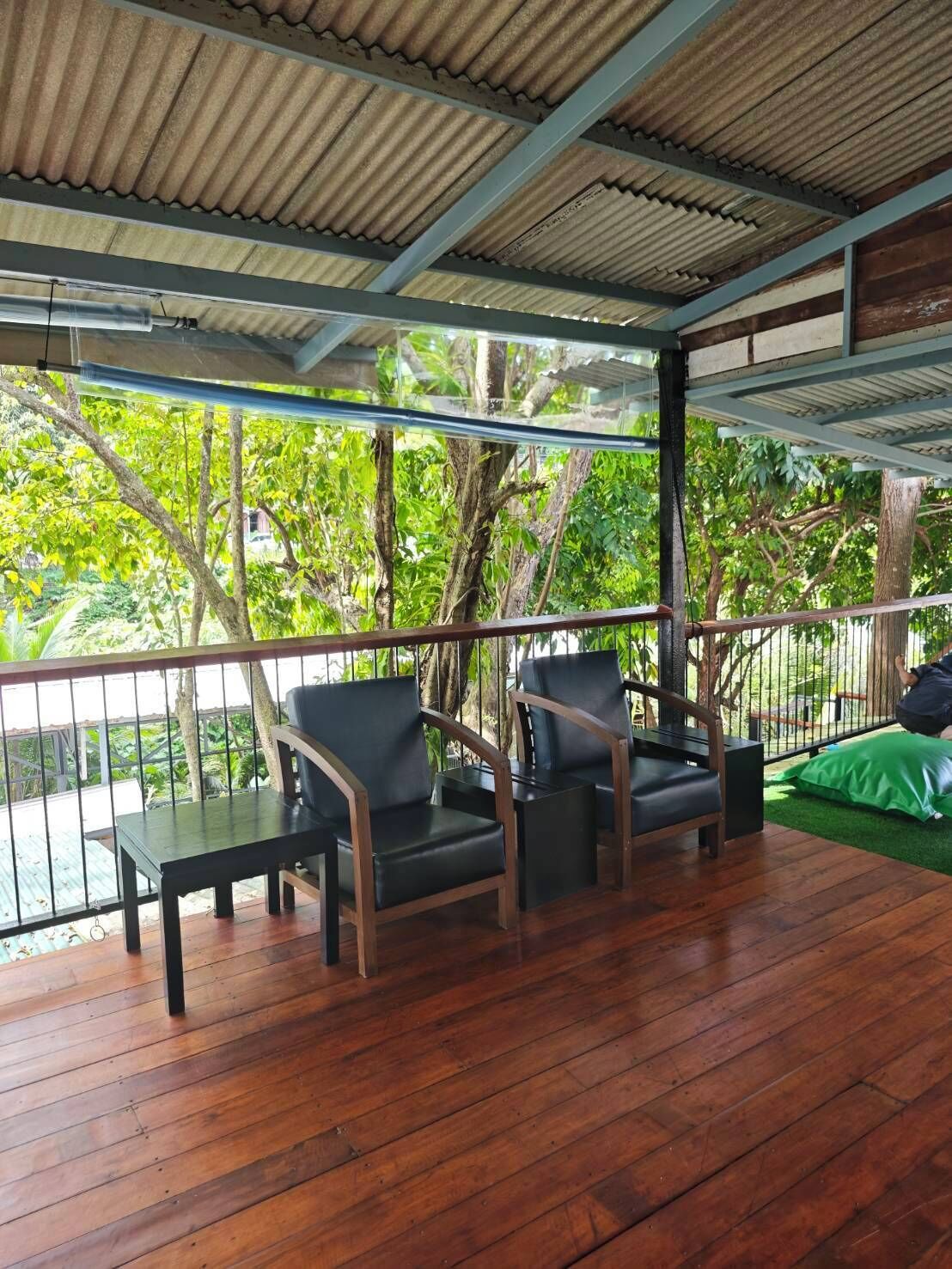 Un espace extérieur abrité, doté d’un plancher en bois, de rampes en métal et de chaises.
