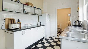 A kitchen with white cabinets, a black and white checkered floor, a toaster, a refrigerator, and a sink.
