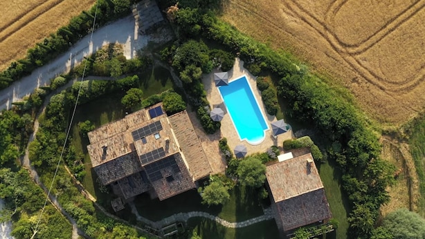 An aerial view of a residential area with a swimming pool, multiple buildings, and surrounding greenery.