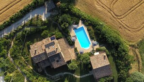 Vue aérienne d’un quartier résidentiel avec une piscine, plusieurs bâtiments et de nombreux espaces verts.