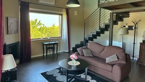 A living room with a sofa, a coffee table, a staircase, and a window with curtains.