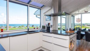 Una cocina moderna con ventanas amplias, una isla central y vistas al mar.