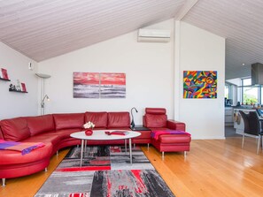 A modern living room with a red sectional sofa, a round coffee table, and a colorful abstract painting.