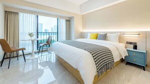 A modern hotel room with a large bed, a bedside table with a lamp, a chair, and a balcony with curtains. - Linjiang Shangpin Apartment (Guangzhou)
