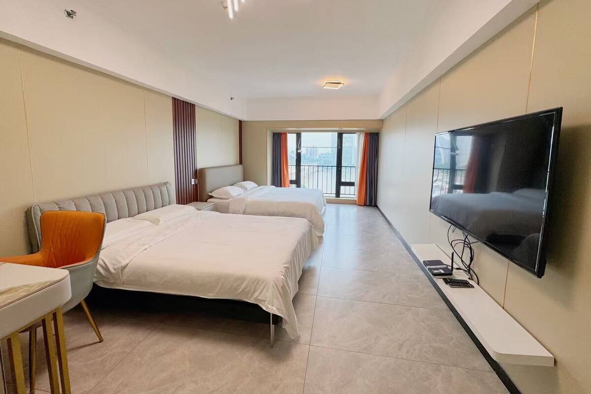 Une chambre d’hôtel avec deux lits, une télévision, un bureau et une grande fenêtre avec des rideaux.