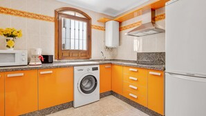 Eine Küche mit Waschmaschine, Mikrowelle und Kühlschrank.