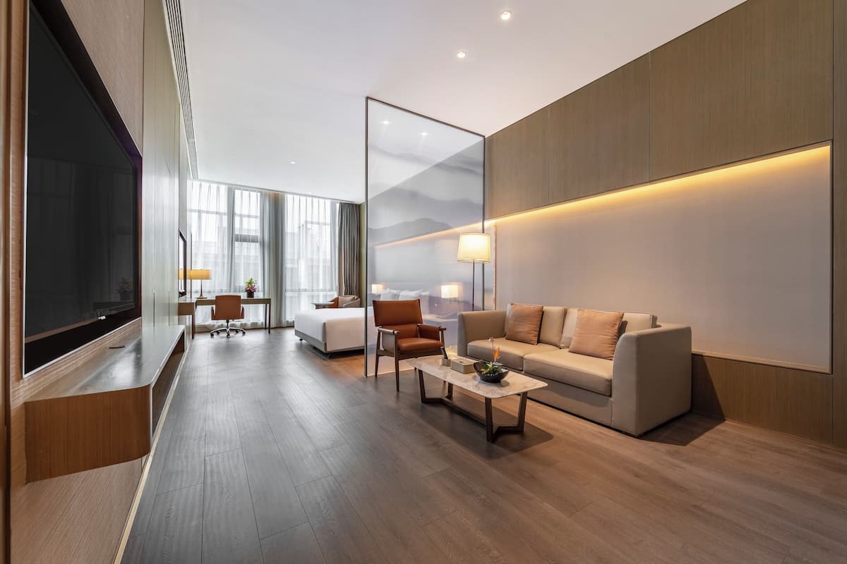 Una sala de estar moderna con una televisión de pantalla plana grande, un sofá, una mesa de centro y un escritorio con una silla.