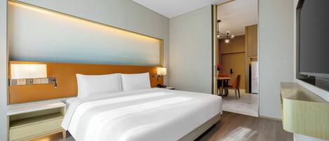Een moderne hotelkamer met een groot bed, nachtkastjes, een flatscreen-tv en uitzicht op de eetruimte.