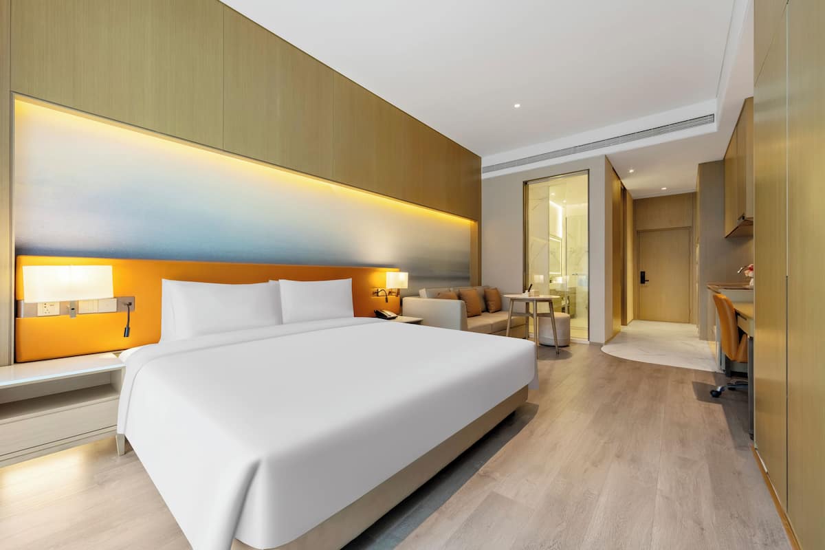 Una habitación de hotel con una cama grande, mesitas de noche, un escritorio y una silla.