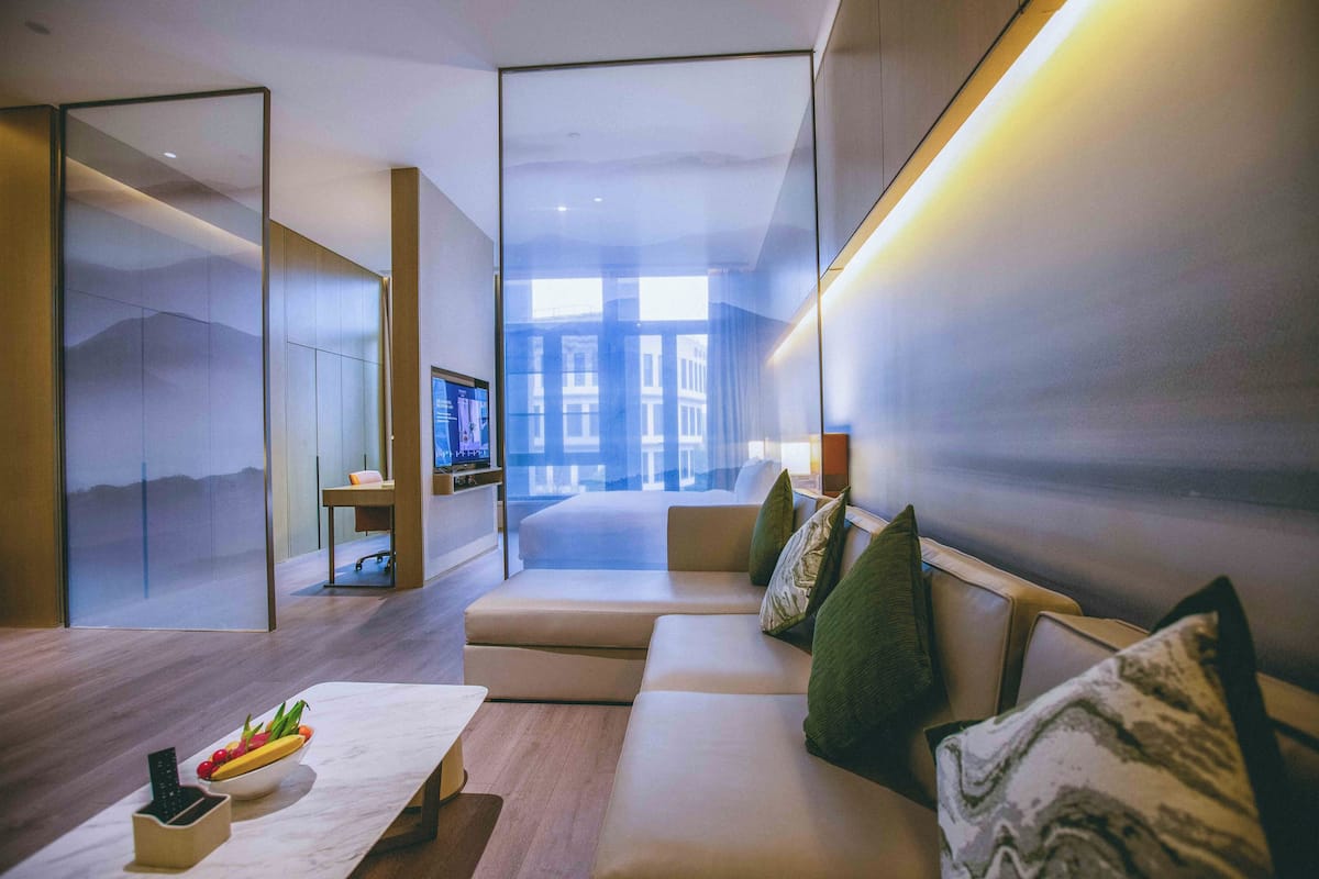 Una habitación de hotel moderna con sofá, mesa de comedor y televisión.