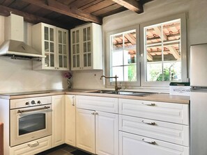 A kitchen with white cabinets, a built-in oven, a sink, and a window with a view of greenery. - Apartment Lucy 1, Milna, Island Brac, Croatia (Milna)