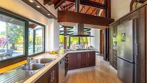 A modern kitchen with dark cabinetry, stainless steel appliances, and a large island. - Cottage House - Adult Only (Kemer)