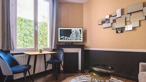 Une pièce comprenant un coin repas, un téléviseur et un tapis à motifs zébrés.