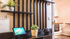 Une cuisine moderne dotée d’un four encastré, d’un petit îlot central avec un ordinateur portable et des plantes en pot, ainsi que d’un haut-parleur noir.
