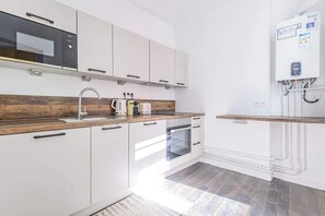 A modern kitchen with white cabinetry, a microwave, a toaster, and a built-in oven. - MM Suites Reims Centre (Reims)