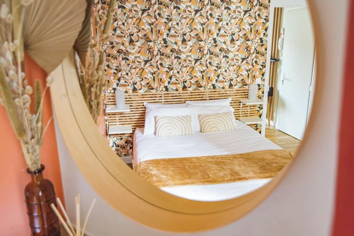 Une chambre avec un lit, une table de chevet et un mur orné d’un motif géométrique.