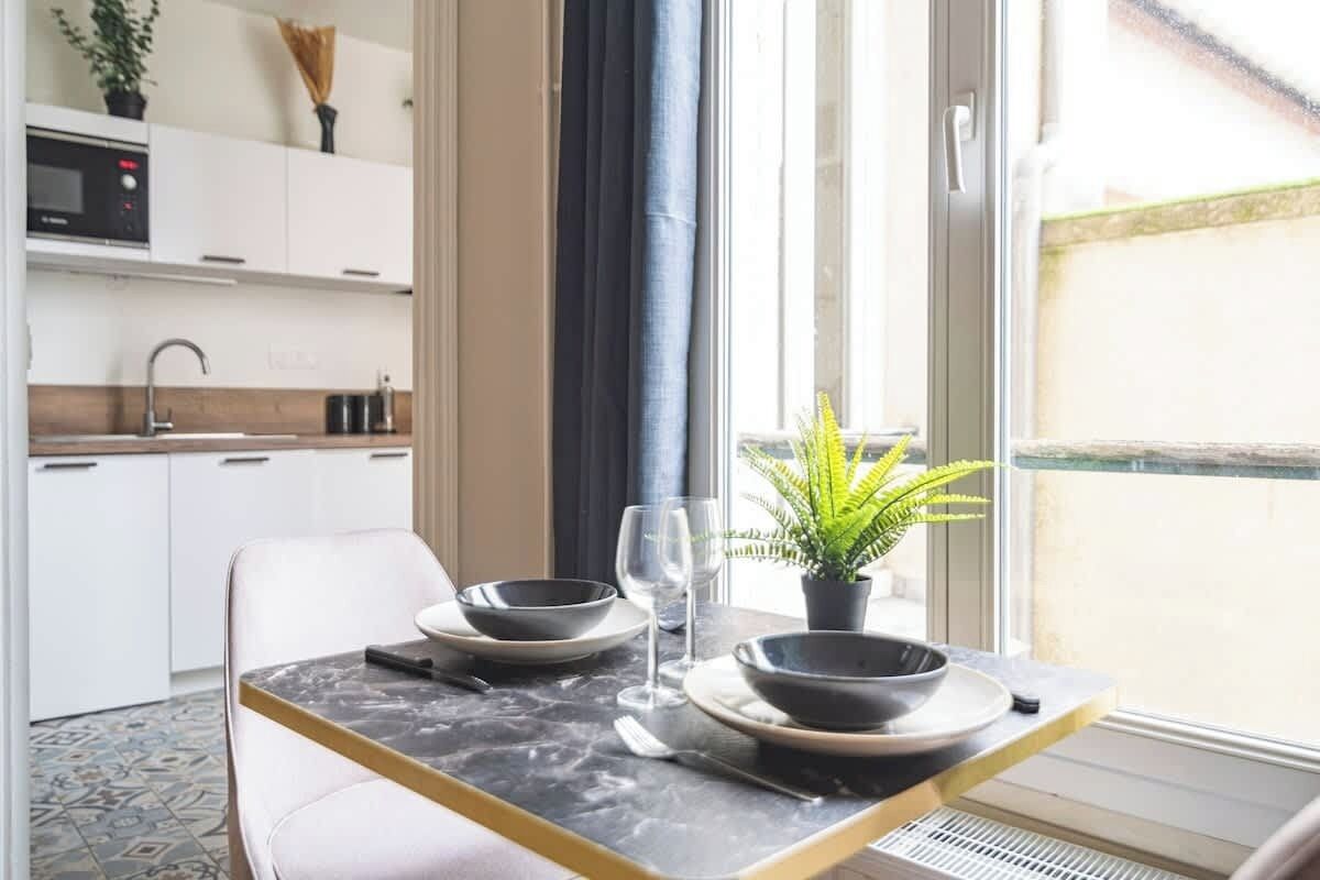 Een eetruimte met een tafel gedekt voor twee personen, een potplant en uitzicht op het buitengebied.