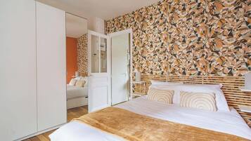 Een slaapkamer met een bed, een kledingkast en een muur met een geometrisch patroon.