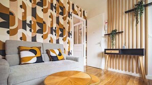 A modern living room with a grey sofa, two round wooden coffee tables, and a patterned wall.