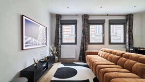 A modern living room with a sofa, a black and white rug, a black console table, and a framed picture on the wall. - MM Suites Town House Terrasse (Reims)