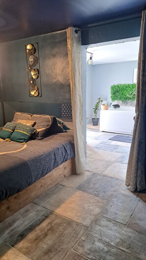Un dormitorio con cama, un panel decorativo en la pared y vistas a un baño y zona exterior.