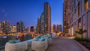 Terraza frente al agua con asientos al aire libre y el horizonte de la ciudad al fondo.
