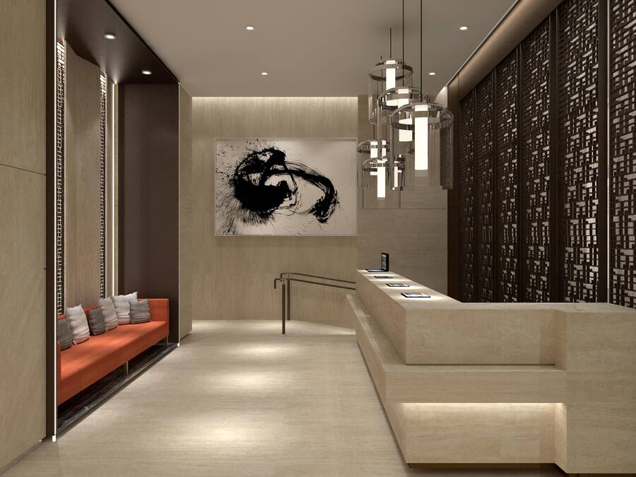 A modern hotel lobby with a reception desk, a sofa with cushions, a large abstract painting, and a decorative wall with a lattice pattern.