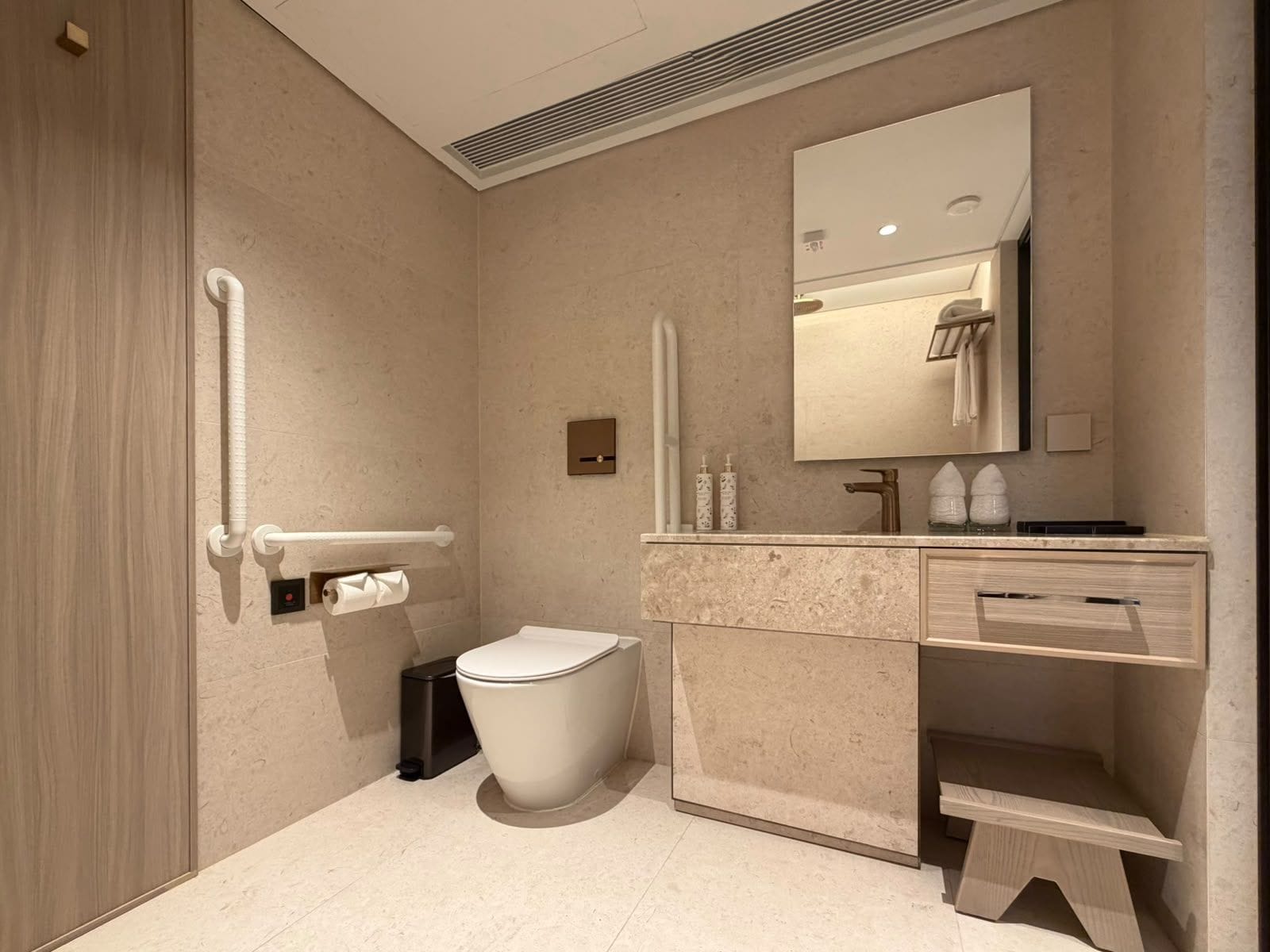 A modern bathroom with a toilet, sink, and mirror.