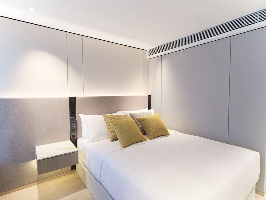 A modern bedroom with a large bed, a bedside table, and built-in storage cabinets.