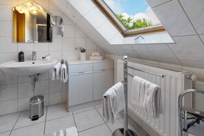 A modern bathroom with a skylight, a white sink, a mirror, and a towel rack. - Apartment '1' with Shared Terrace, Shared Garden and Wi-Fi (Nordstrand)