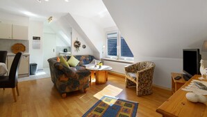 Ein Loft-Wohnraum mit Küche, Essbereich und einer Sitzecke mit gemusterten Möbeln.