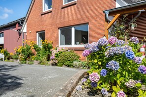 Een woongebouw met een bakstenen gevel, ramen en een tuin met hortensia’s.