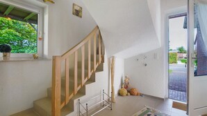 Eine Treppe mit Holzboden und Metallgeländer, ein Besen und eine kleine Figur auf dem Boden.